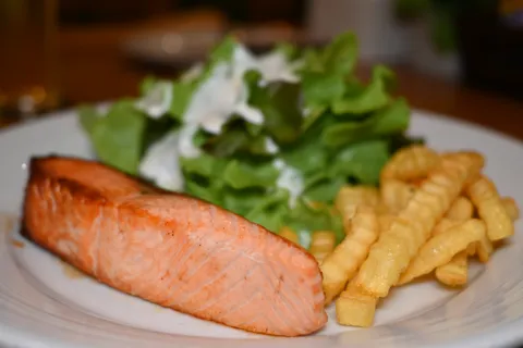 Lachs mit Pommes und grünem Salat auf einem Teller